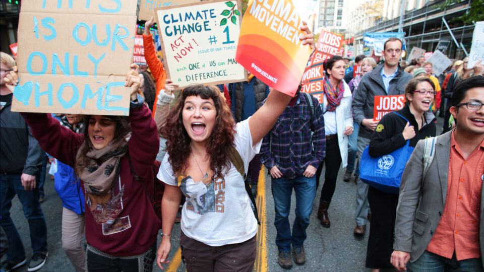 Young person holding up sign while marching in climate change protest