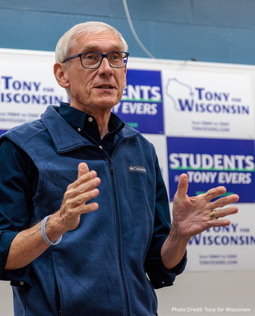 Gov. Tony Evers photographed speaking in front of campaign signs.